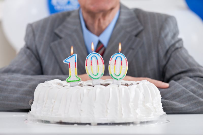 birthday cake with lit candles for a century, one hundredth birthday